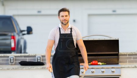 Photo for Male chef grilling and barbequing in garden. Barbecue outdoor garden party. Handsome man cook preparing barbecue meat. Concept of eating and cooking outdoor during summer time - Royalty Free Image