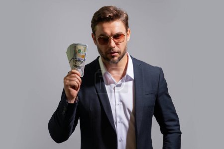 Photo for Business man hold money on gray studio isolated background. Rich man in suit with money dollar bills. Successful businessman with dollar banknotes. Rich millionaire in suit holding money - Royalty Free Image