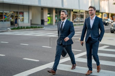 Photo for Businessmen couple walking across the crosswalk on american city street outdoor. Cheerful middle eastern businessman walking by street. Portrait of successful business people outdoor - Royalty Free Image