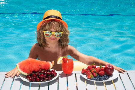 Téléchargez les photos : Portrait d'enfants d'été. Enfant dans la piscine avec fruits d'été. Vacances d'été pour enfants. Plage et eau de mer amusant. Vacances d'été et vacances, manger sainement pour les enfants - en image libre de droit