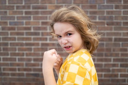 Photo for Child temper with angry expression. Angry hateful little anger boy, child furious. Angry rage kids face close up. Anger hateful child with furious emotion portrait. Aggressive and mad kid behavior - Royalty Free Image
