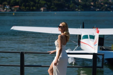 Téléchargez les photos : Fashion young woman in stylish dress walking near jet. Woman tourist getting out of jet airplane. Summer destination travel. Summer vacation on Como lake Italy. Travel and active lifestyle concept - en image libre de droit