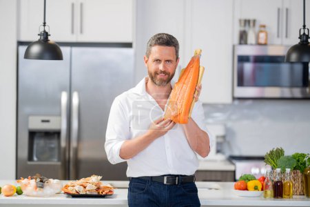 Photo for Chef man cooking seafood crab and shrimp, salmon and lobster in kitchen. Cook guy in white shirt on kitchen with salmon fillet. Salmon recipes. Baked salmon fillet - Royalty Free Image