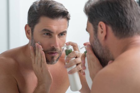 Photo for Male model applying cosmetic cream on face. Facial treatment. Beauty portrait of man applying face cream. Skin care product. Moisturizing creme for wrinkle face skin. Perfect skin, morning routine - Royalty Free Image