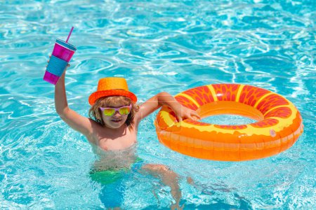 Foto de Niño en piscina en anillo inflable. Los niños nadan con flotador naranja. Juguete acuático, actividad deportiva al aire libre saludable para niños. Niños diversión en la playa. Cóctel de verano para niños - Imagen libre de derechos