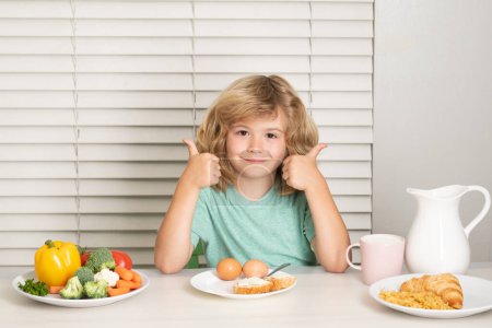 Foto de Niño comiendo alimentos saludables vegetales. Desayuno con leche, frutas y verduras. Niño comiendo durante el almuerzo o la cena - Imagen libre de derechos