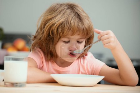 Téléchargez les photos : Enfant mangeant des aliments sains. Mignon petit garçon manger de la soupe pour le déjeuner - en image libre de droit