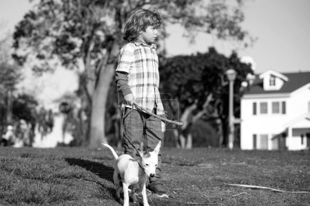 Foto de Niño encantador con perro paseando al aire libre. Niño con su amigo mascota - Imagen libre de derechos