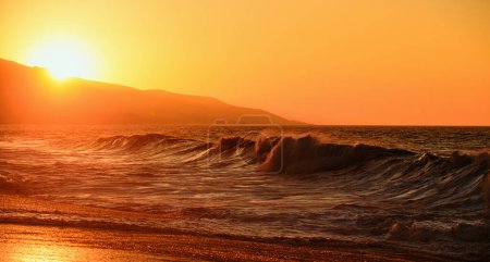Foto de Cielo dorado y agua de mar. Playa tropical con suave ola y atardecer cielo abstracto de fondo. Amanecer dorado puesta de sol sobre las olas del mar. Salida del sol sobre el océano. Salpicaduras de olas - Imagen libre de derechos