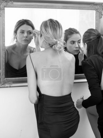 Photo for Glamour portrait of beautiful girl model with makeup. Fashion shiny highlighter on skin. Women girlfriends applying make-up preparing for party, looking in mirror - Royalty Free Image