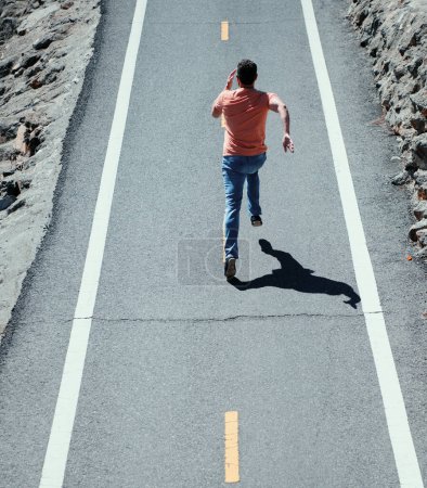 Téléchargez les photos : Vue arrière de l'homme courant sur la route. Jeune homme athlétique courir en plein air - en image libre de droit