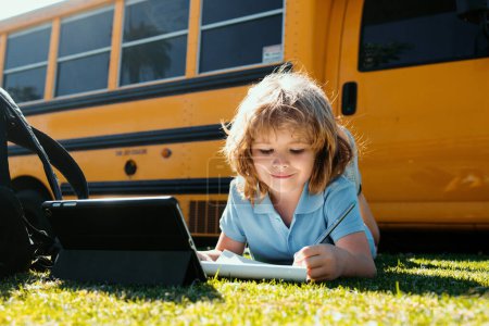 Foto de De vuelta a la escuela. Feliz estudio infantil en el parque. Niño de la escuela haciendo tarea o educación en línea - Imagen libre de derechos