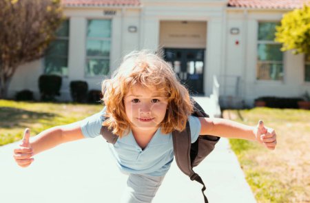 Foto de De vuelta a la escuela. Lindo chico con mochila corriendo e ir a la escuela y mostrar los pulgares hacia arriba. Niño primer día en la escuela - Imagen libre de derechos