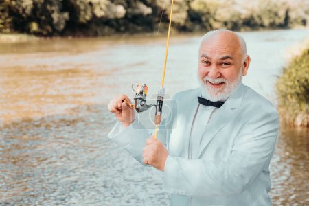 Photo for Fisherman in formal suit. Man fishing on river. Catch me if you can. Man relaxing and fishing by lakeside. Man at riverside enjoy peaceful idyllic landscape while fishing. Retired father - Royalty Free Image