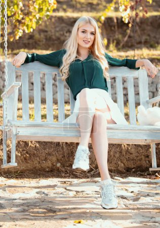 Téléchargez les photos : Jeune femme sexy se balance sur une balançoire dans le jardin du parc d'été. Sensuelle fille blonde reposant dans le salon - en image libre de droit