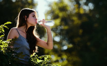 Téléchargez les photos : Femme saine buvant de l'eau de bouteille en plein air. Restez hydratation concept. Non cachée. Unité avec la nature - en image libre de droit