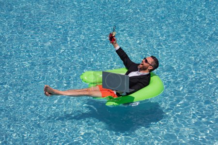 Photo for Businessman working on-line outdoor. Travel destinations, summer vacations. Funny business man in suit on summer holiday at sea beach water. Crazy entrepreneur using laptop on vacation - Royalty Free Image
