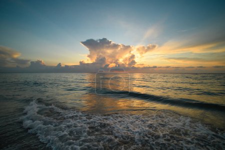 Foto de Puesta de sol en la playa tropical mar océano con nubes del amanecer. Banner para vacaciones de viaje. Paisaje cielo y reflejos rayos en el agua. Salida del sol en la playa sobre el mar tropical. Tranquilo, fondo dorado del cielo - Imagen libre de derechos
