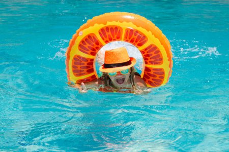 Photo for Kid swim with floating ring in swimming pool. Kids summer vacation. Happy child boy with inflatable ring in poolside. Vacations and summer recreation with children - Royalty Free Image
