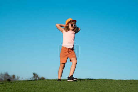 Foto de Niño corriendo sobre hierba verde cerca del cielo azul en el parque de primavera. Niño jugando y corriendo en el parque de verano - Imagen libre de derechos