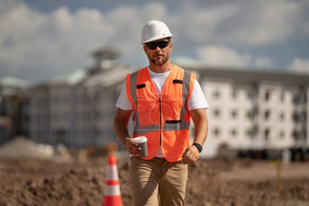 Photo for Worker in building uniform on buildings construction background. Builder at the construction site. Man worker with helmet on construction site. Bilder in hardhat - Royalty Free Image