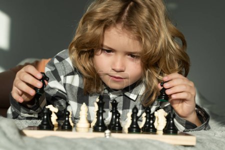 Foto de Lindo niño jugando ajedrez en casa. Ajedrez para chico inteligente. Niño genio, alumno inteligente jugando juego de mesa lógica. Chico listo pensando en ajedrez - Imagen libre de derechos