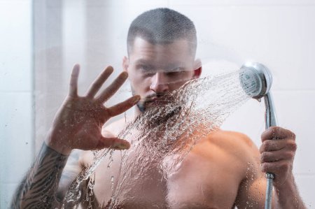 Foto de Retrato de hombre desnudo tomando ducha en el baño. Rutina de higiene masculina. Hombre sexy con lavado corporal muscular húmedo en la ducha. Un tipo en la ducha. Un hombre tomando una ducha caliente. Rutina matinal - Imagen libre de derechos