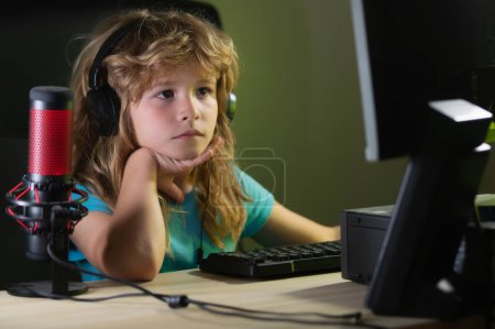 Téléchargez les photos : Petite enfant blogueuse. Kid Boy enregistrant un podcast sur ordinateur. Portrait d'enfant mignon tout en tapant sur le clavier - en image libre de droit