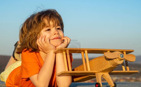 Photo for Child boy playing with wooden toy airplane, dream of becoming a pilot. Childrens dreams. Child pilot aviator with wooden plane. Summer holidays with children - Royalty Free Image