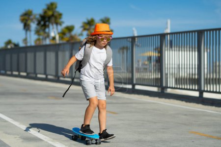 Photo for Child on skateboard skating. Young boy on his skateboard striking and practices his skill at the skate park. Happy child having fun on summer holidays - Royalty Free Image
