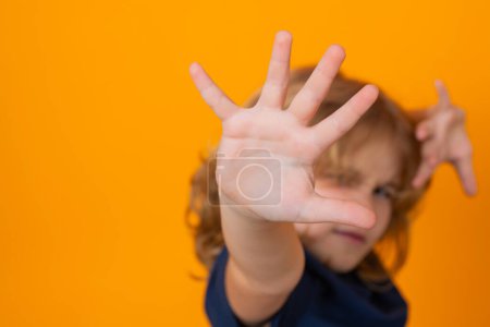 Foto de Niño haciendo gesto de parada sobre fondo de estudio aislado amarillo. Muchacho mostrando símbolo de advertencia, señal de mano no. Protección de los niños, acoso escolar y concepto de violencia - Imagen libre de derechos