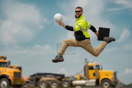 Photo for Construction worker excited jump on construction site. Construction engineer worker in builder uniform on construction. Portrait of builder ready to build new house - Royalty Free Image