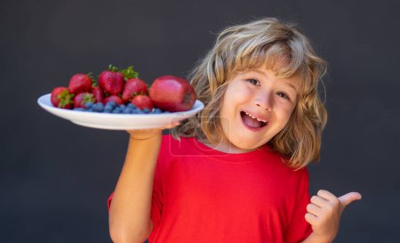 Photo for Healthy food. Funny kid with thumb up hold plate of mix summer fruits. Healthy organic strawberry fruit, summer season - Royalty Free Image