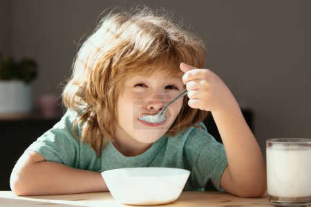 Téléchargez les photos : Un enfant mange. Petit garçon affamé en bonne santé mangeant de la soupe à partir de cuillère - en image libre de droit