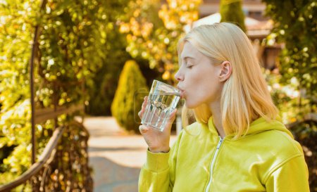 Foto de Mujer joven bebiendo agua en el parque de otoño. Estilo de vida activo en otoño día soleado al aire libre. Chica usando suéter brillante en increíbles hojas otoñales de fondo - Imagen libre de derechos