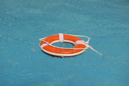 Téléchargez les photos : Pas de baignade. Équipement d'urgence de sauvetage en eau. Anneau de sauvetage flottant dans l'eau claire de la piscine. Été - en image libre de droit
