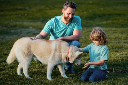 Foto de Sonriente Padre e Hijo con Mascota. Familia feliz con perro pedigrí leal divertirse en el patio trasero - Imagen libre de derechos