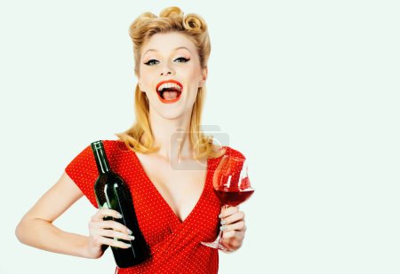 Foto de Hermosa mujer bebiendo vino tinto. Labios rojos y vestido rojo. Retrato de mujer hermosa con vino tinto de cristal. Aislado sobre fondo blanco - Imagen libre de derechos