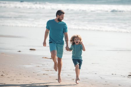 Téléchargez les photos : Père et fils courent sur la mer. Concept de famille amicale et de vacances d'été - en image libre de droit
