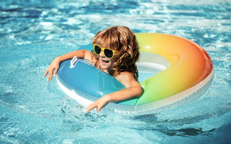 Téléchargez les photos : Vacances d'été. Week-end d'été. Garçon drôle dans la piscine sur le cercle en caoutchouc gonflable à aquapark - en image libre de droit