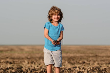 Téléchargez les photos : L'enfant tient la terre, le sol. Enfance à la campagne - en image libre de droit