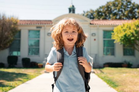 Foto de Cara divertida del chico de la escuela. Pul infantil con mochilas en el parque cerca de la escuela. Colegial con mochilas al aire libre - Imagen libre de derechos