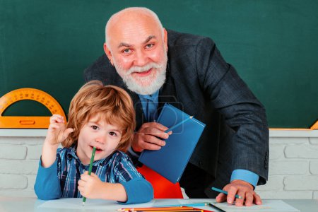 Foto de Abuelo maestro con nieto alumno en la parte posterior del aula en la escuela primaria. Concepto de educación científica - Imagen libre de derechos