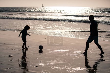Photo for Father and son play soccer or football on the beach - Royalty Free Image