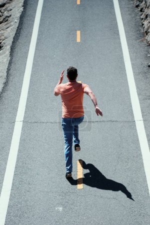 Foto de Vista trasera del corredor del hombre corriendo en la carretera. Concepto urbano de entrenamiento - Imagen libre de derechos