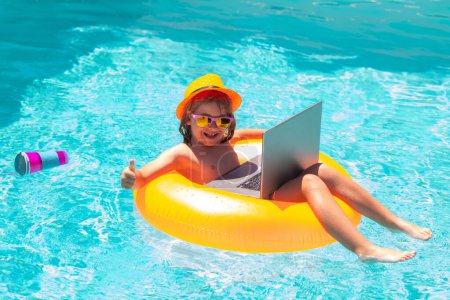 Téléchargez les photos : Voyages d'affaires. Enfant avec ordinateur portable dans l'eau de la piscine pendant la journée d'été. Ordinateur portable étanche - en image libre de droit