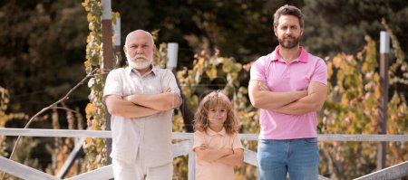Photo for Male generation family together with three different generations ages grandfather father and son in summer garden - Royalty Free Image