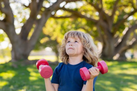 Photo for Kids sport training in summer park outdoor. Kid boy working out with dumbbells. Sport and kids training - Royalty Free Image