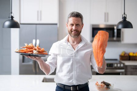 Photo for Chef man cooking seafood crab and shrimp, salmon and lobster in kitchen. Cook on kitchen with salmon fillet. Salmon recipes. Baked salmon fillet - Royalty Free Image