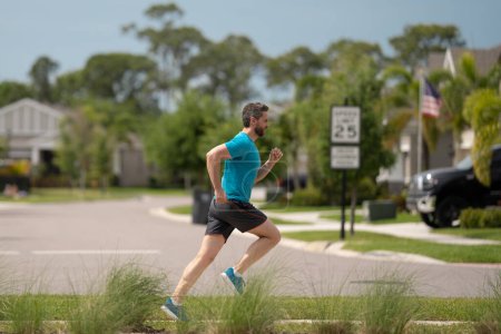 Photo for Handsome middle aged man running across american neighborhood. Athletic man running outdoor. Healthy lifestyle. Active healthy runner jogging outdoor - Royalty Free Image